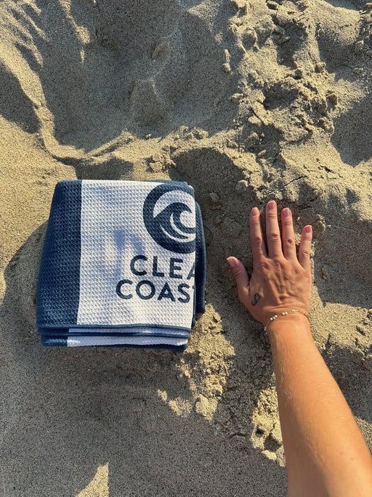 Clean Coastal compact beach towel shown beside a hand for scale
