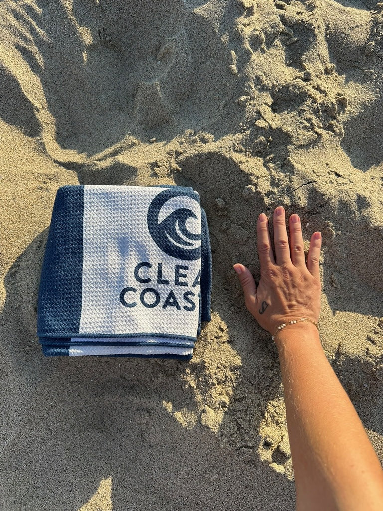 Clean Coastal compact beach towel shown beside a hand for scale