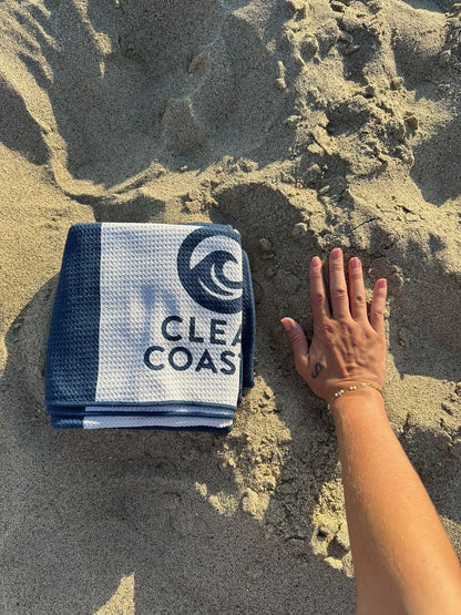 Clean Coastal compact beach towel shown beside a hand for scale